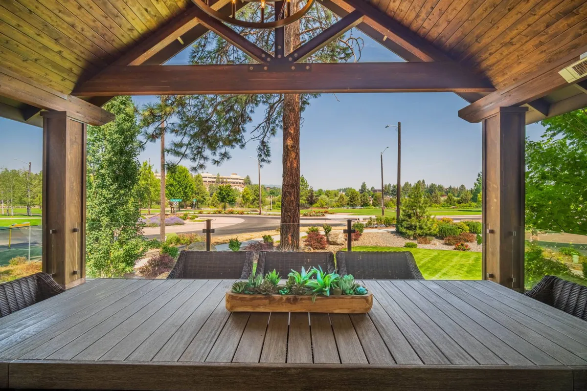 A serene exterior setting featuring a wooden outdoor dining table with a succulent centerpiece, overlooking lush greenery. The space speaks to the experience of relaxing after adventures or enjoying meals outdoors amidst nature.