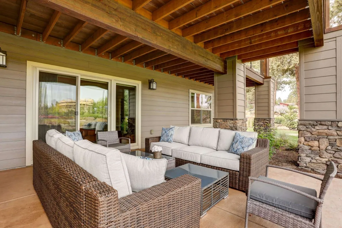 A comfortable seating area indoors with large windows providing expansive views of the outdoors. The room features stone accents and is designed for relaxation, socializing, and enjoying beautiful sunsets or nature views. The space invites both summer and winter enjoyment, making it ideal for gatherings or unwinding after a day of adventure.