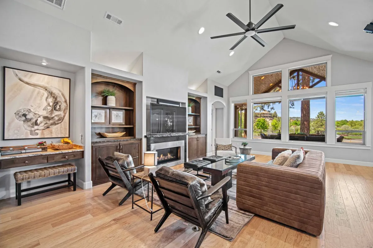 A serene, inviting living area with large windows framing views of nature, a modern fireplace for cozying up in winter, and stylish decor for both relaxing and entertaining. The space balances comfort and connection to the outdoors, ideal for après-ski evenings or watching seasonal changes.