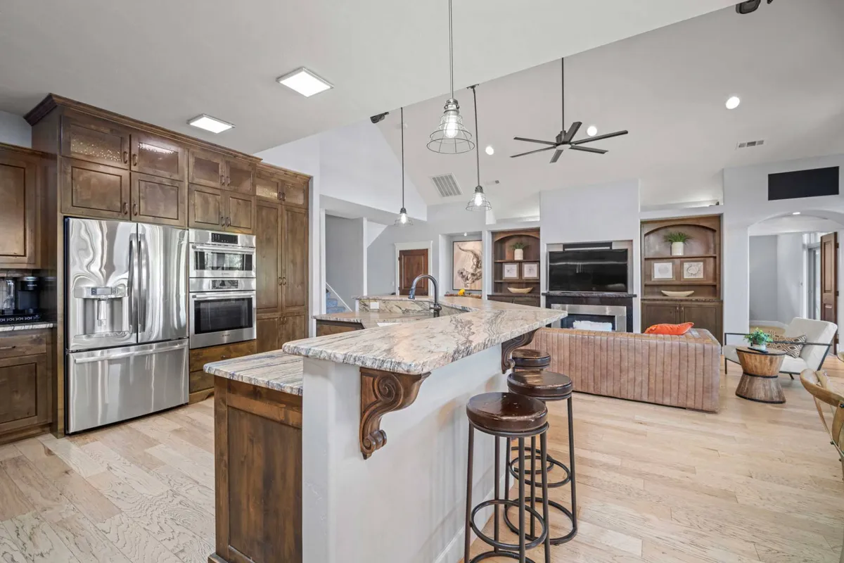 A view of an open kitchen with a central island, stainless steel appliances, granite countertops, and direct connection to the living area. The space is inviting and designed for group cooking and entertaining, seamlessly integrating the kitchen with the social spaces.