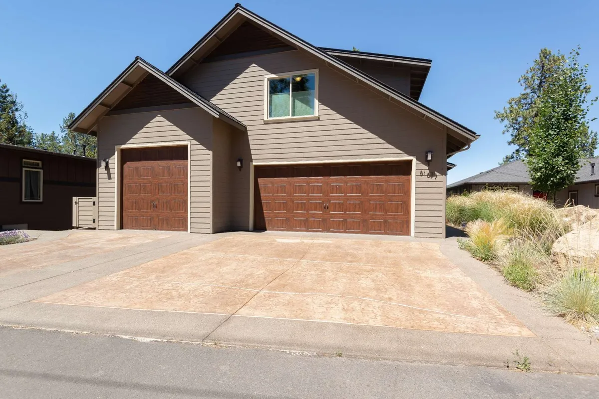 An exterior view of the home featuring a two-car garage, a textured driveway, and a landscaped border. The front of the house is welcoming and provides a sense of arrival, offering a glimpse of the home’s scale and its inviting presence for multiple families or a group of friends.